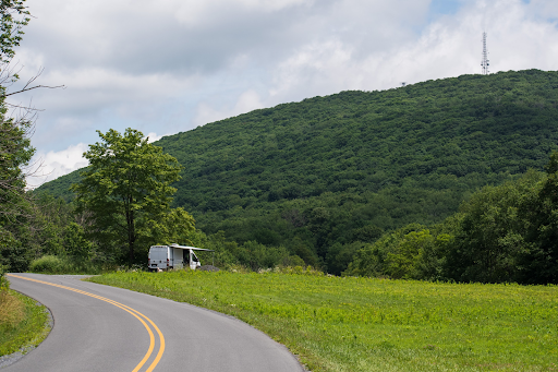 Road winding through green hills with van parked in the distance.