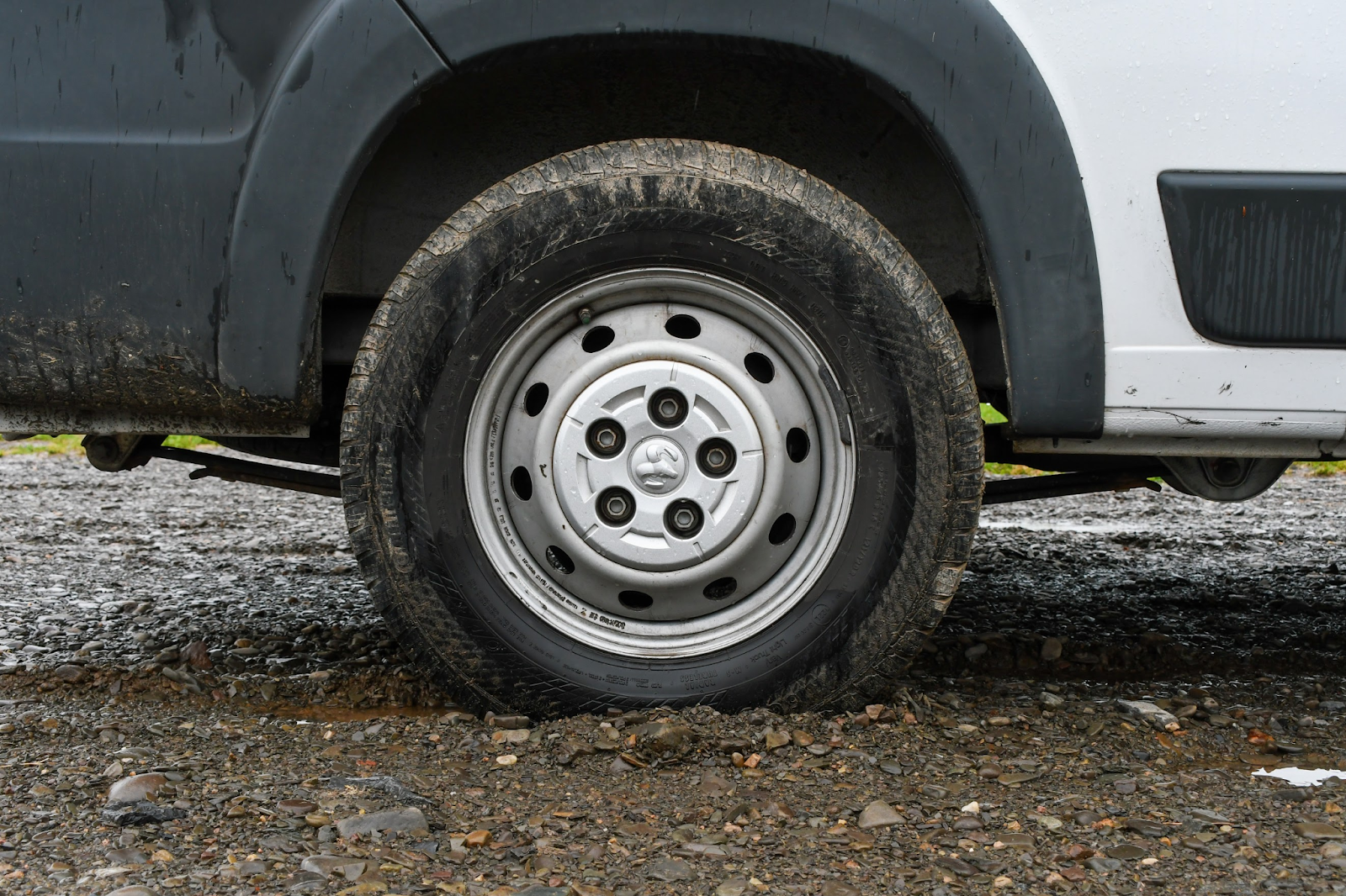 Closeup of a van tire sunken in mud.