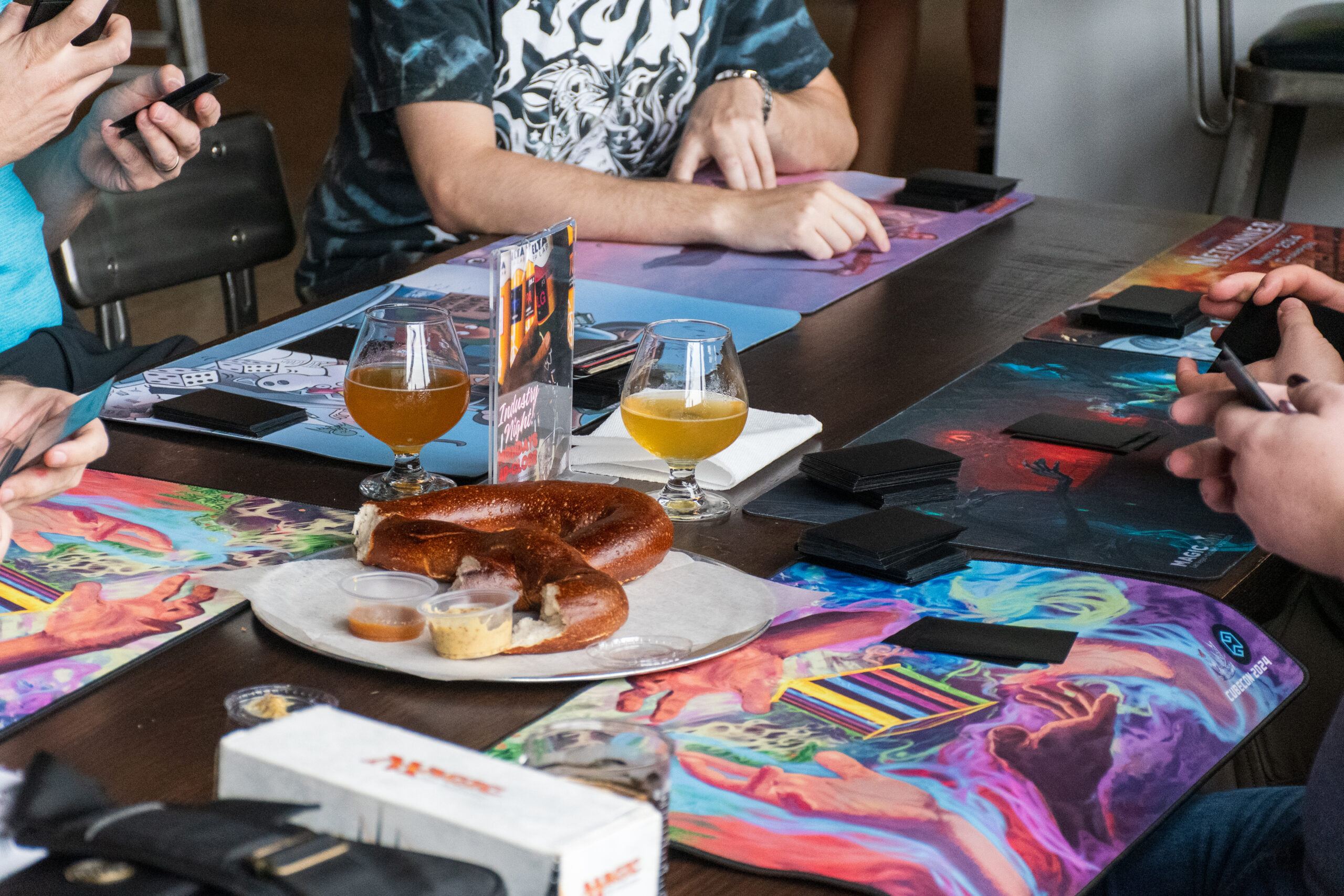 Hands sort stacks of Magic cards with a table full of beer and pretzels