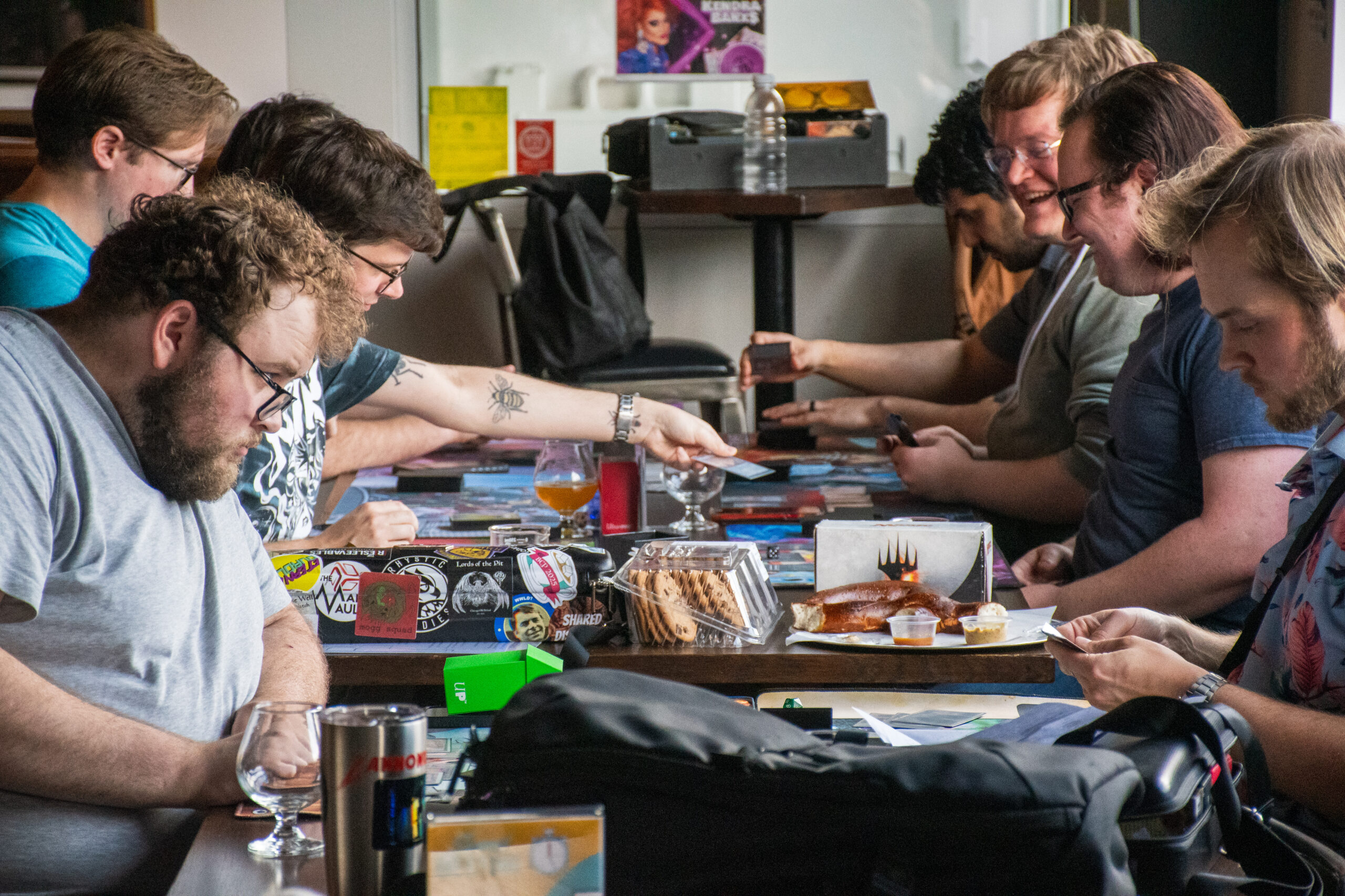 A side profile of a table full of people playing Magic at a brewery