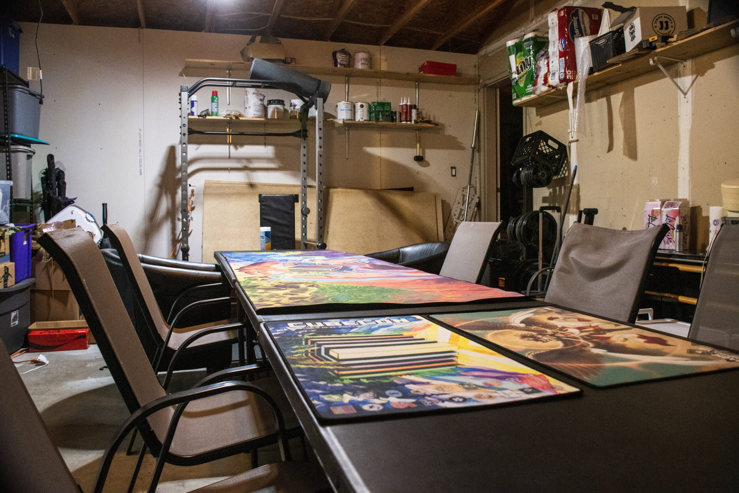 a garage with a set of plastic tables set up, featuring play mats and sling back patio chairs