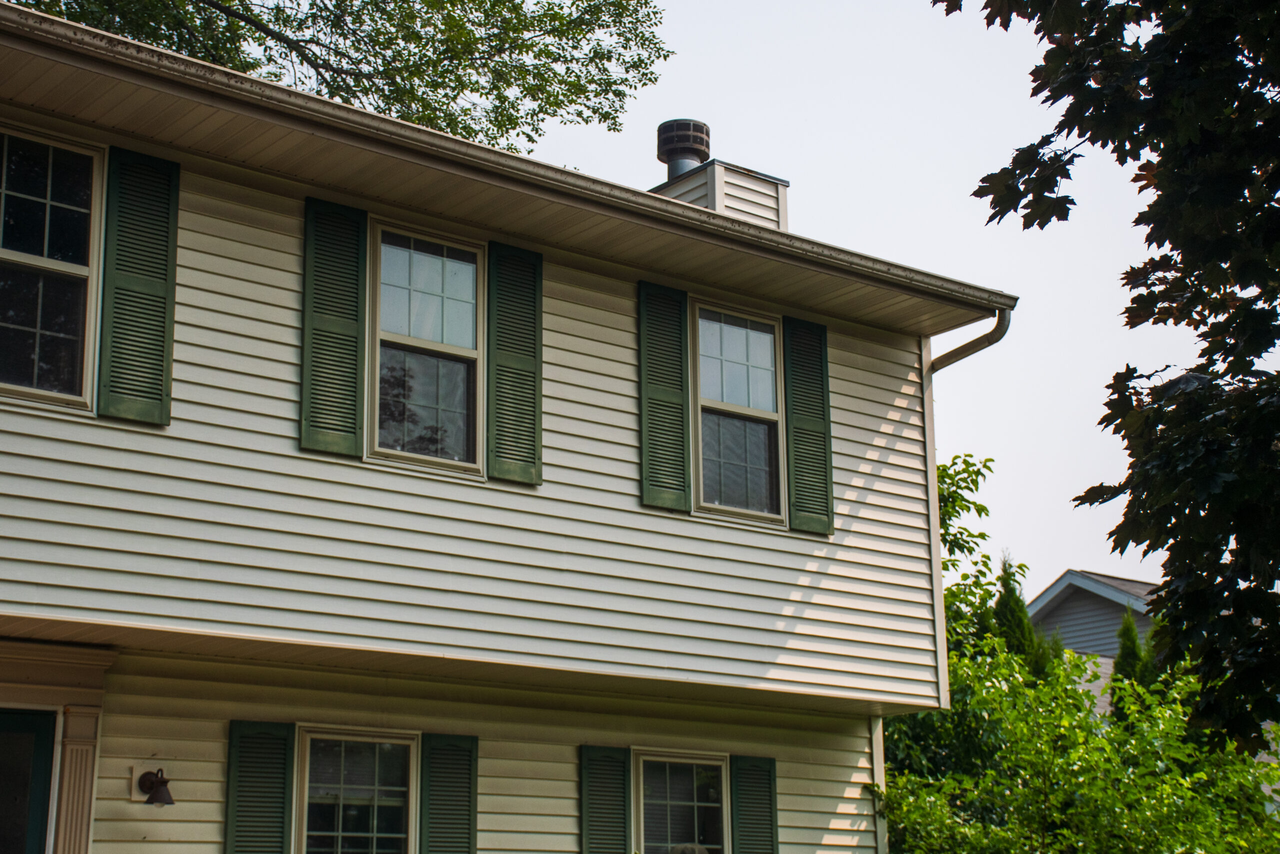 A white two-story colonial house with green shutters